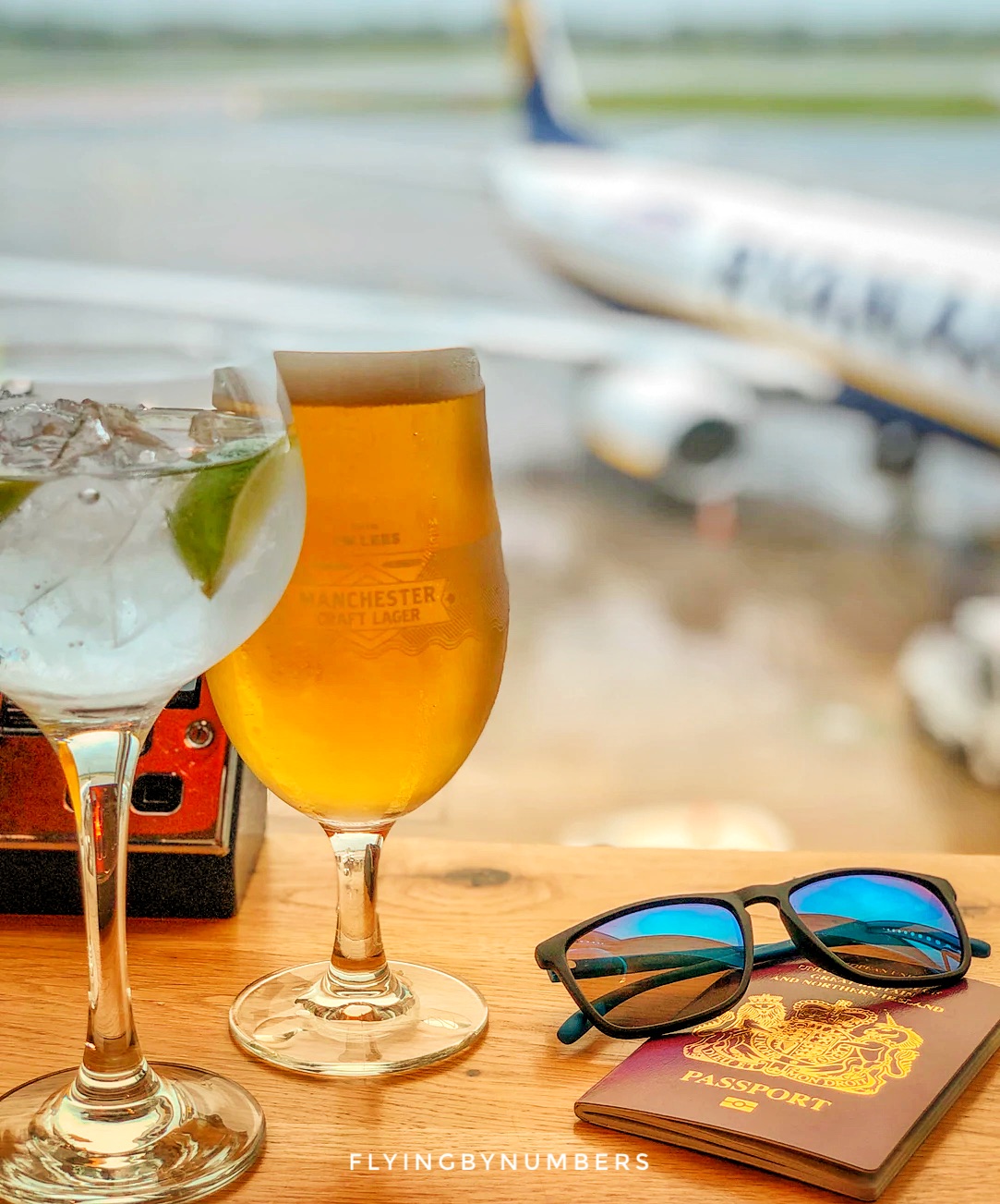 Passport glasses and alcoholic drinks in front of commercial plane