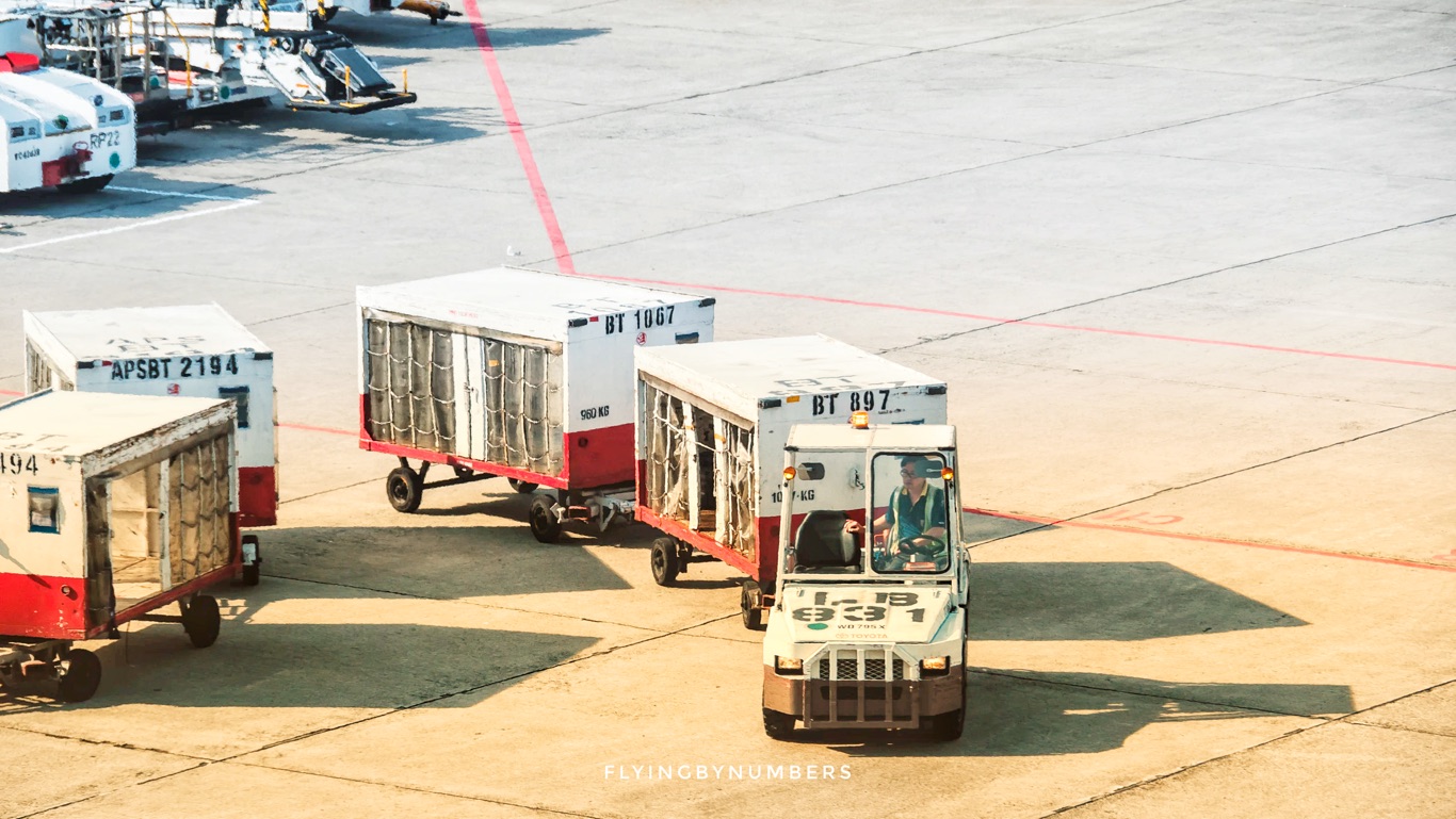 baggage handler with crates left on tarmac