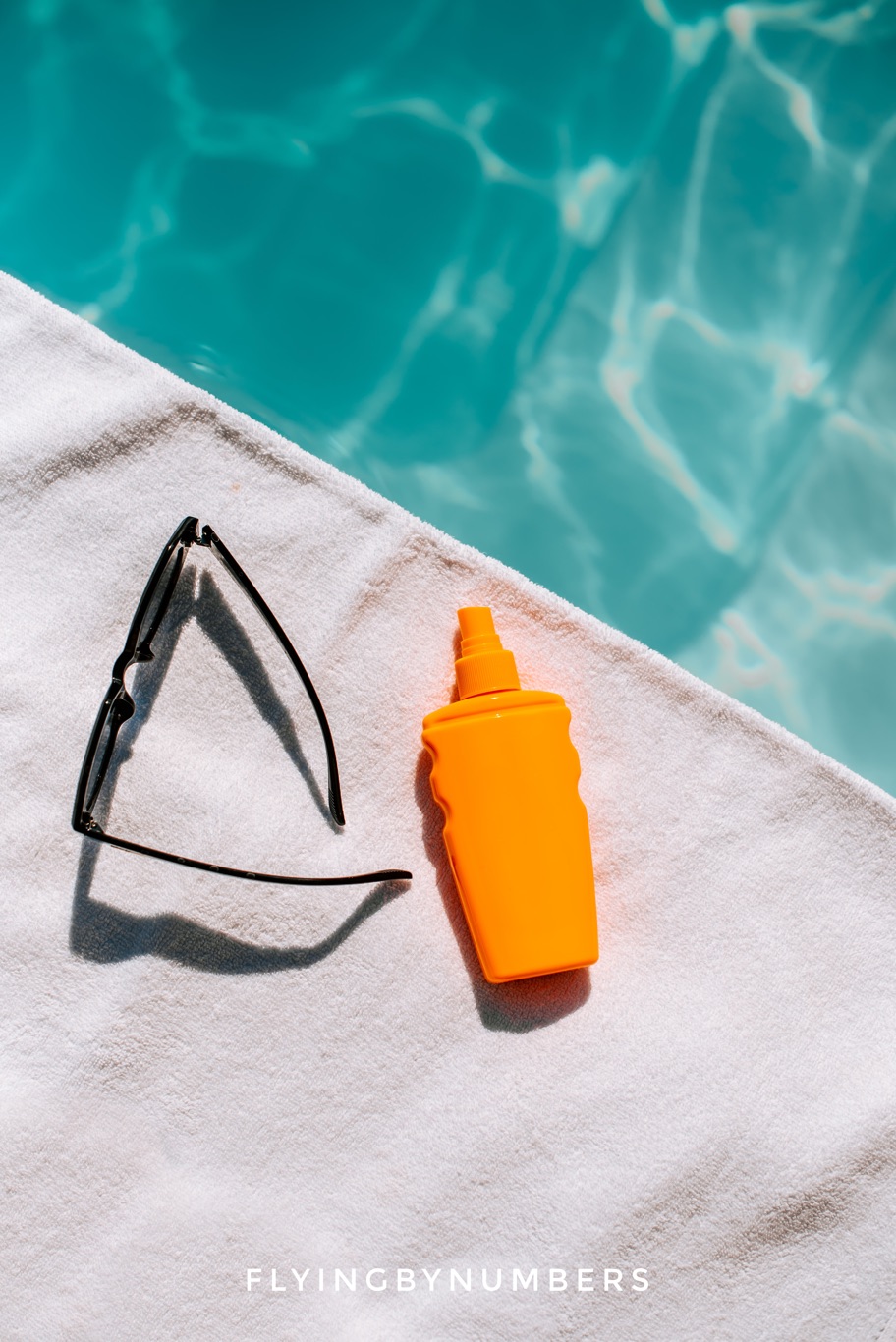 Suncream and glasses by a pool