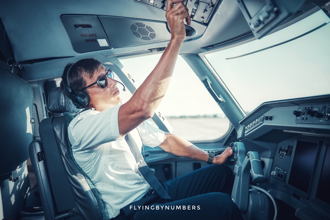 Airline pilot adjusts overhead switches in commercial aircraft cockpit